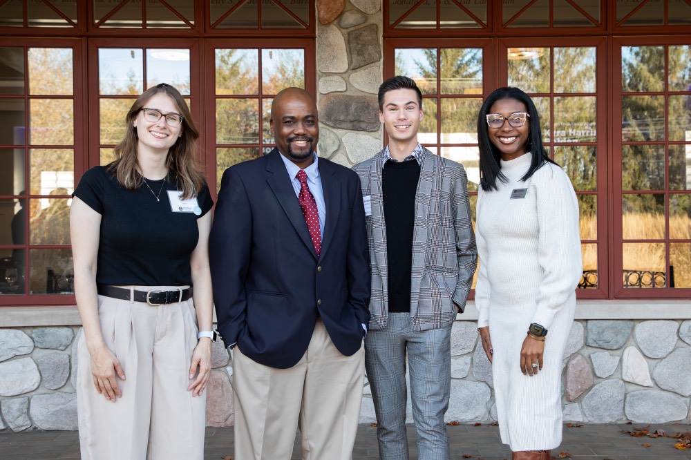 Quincy Williams poses with 3 other people outside Alumni House